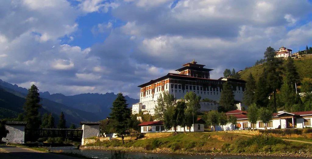 Paro Dzong, a whitewashed fortress monastery on a wooded hillside above the river in Paro, Bhutan